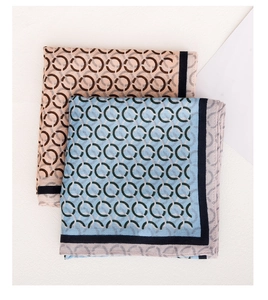 Detail of folded silk scarves with interlocking ring patterns in orange-pink and sky blue