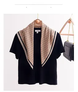 Detail showing apricot scarf with black chain patterns on a wooden hanger with a bag