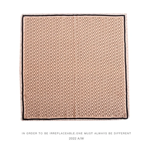 Close-up of a pink silk square scarf with geometric circle patterns and black borders