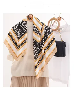 Detail showing elegant leopard print and golden chain pattern on silk scarf fabric