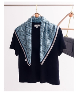 Detail of light blue silk scarf with black chain pattern styled on a black t-shirt