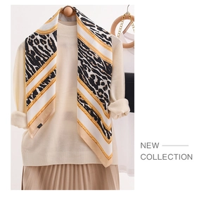 Close-up of leopard and gold chain print silk scarf on white knitted sweater