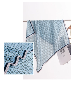 Detail showing high-gloss light blue silk scarf with classic dark blue chain print