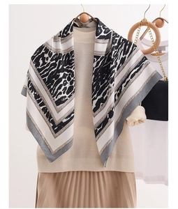Detail of silk scarf with leopard print and chain patterns styled on a beige sweater