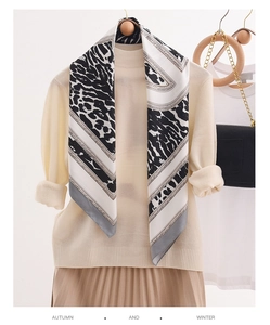 Close-up of leopard print silk scarf with chain pattern paired with beige knitwear