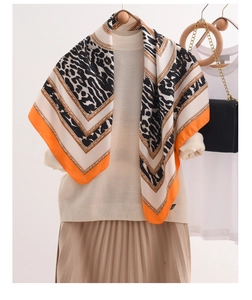 Detailed texture of leopard print silk scarf with vibrant orange edges and chain pattern