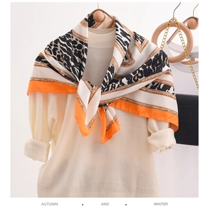 Detail of silk scarf with leopard print and orange border draped over a sweater