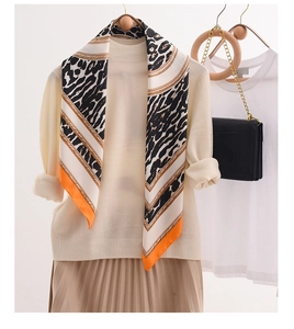 Detail of leopard print silk scarf with golden chain patterns and orange borders