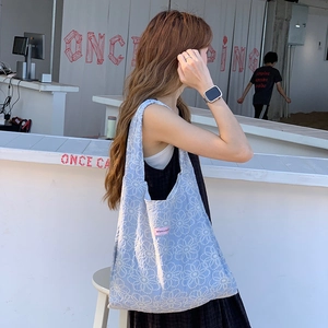 Broderie détaillée de marguerites blanches sur un sac à bandoulière en toile bleu clair