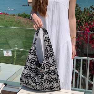 Détails de broderie sur un sac cabas floral noir lors d'une séance photo estivale