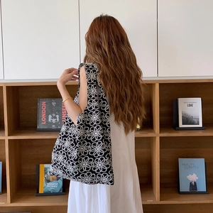 Détail d'un grand sac cabas en tricot noir avec broderie de marguerites blanches chic