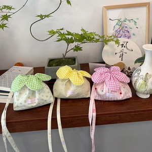 Three pleated plaid shoulder bags in green yellow and pink on a dark wood table