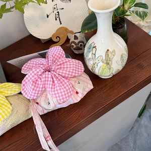 Close-up of floral drawstring bag with pink plaid petals and flower embroidery
