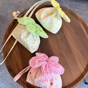 Top view of three cute plaid floral drawstring bags on a round wooden tray