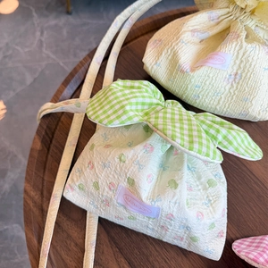 Detail of floral drawstring bags with green plaid bow on a dark wooden tray