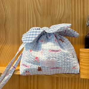 Close-up of seersucker drawstring bag with blue plaid patterns and cute bear illustrations