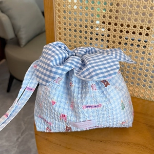 Detail of light blue gingham drawstring bag with cartoon bear prints and a large bow