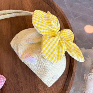 Detail of yellow puffy texture bag with a large checkered bow on wooden tray