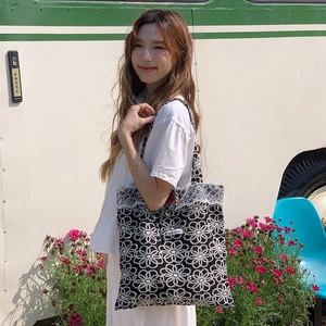 Détail du sac cabas brodé noir avec bordure en dentelle et petit logo discret