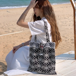 Détail du sac cabas brodé avec fleurs, bordure en dentelle blanche et étiquette logo