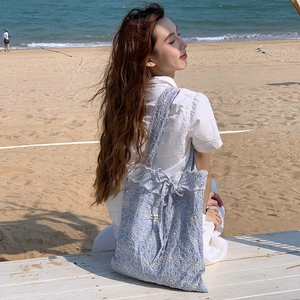 Détail du sac cabas bleu clair en dentelle avec broderie florale et ruban à nœud