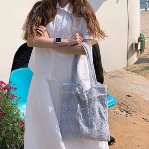 Détail du sac cabas en coton bleu clair avec broderie marguerite et bordure en dentelle