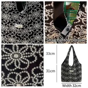 Black canvas tote bag with white floral embroidery and silver metal snap button closure