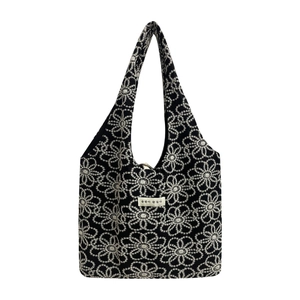 Minimalist black canvas tote bag with white floral embroidery and woven patch