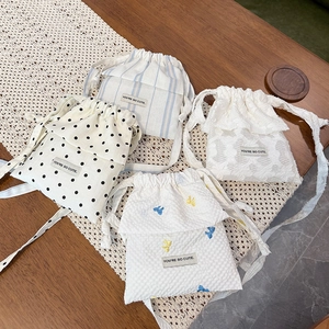 Detail of four drawstring crossbody bags with lace, polka dots and You're So Cute label