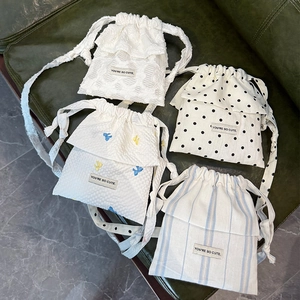 Close-up of four stylish drawstring bags featuring polka dots and bow embroidery details