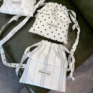 Detailed view of canvas drawstring bags in polka dot, lace, and striped floral patterns
