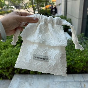 Detail of white jacquard drawstring bag featuring You're So Cute text label