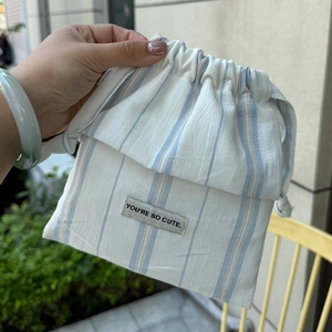 Close-up of drawstring bag with vertical stripes and 'You're so cute' textile label