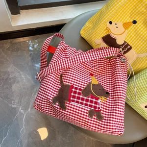 Détail du sac bandoulière en toile vichy avec broderie chien et cordon de serrage rouge