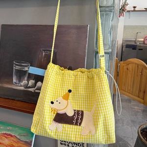 Détail d'un sac en toile à carreaux jaunes avec broderie chiot et fermeture par cordon