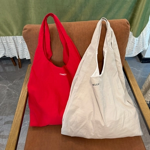 Détail de sacs fourre-tout en nylon rouge et crème avec lettrage Camellia sur siège