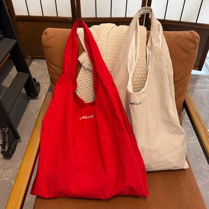 Grands sacs fourre-tout en nylon rouge et beige avec imprimé Camellia sur fauteuil