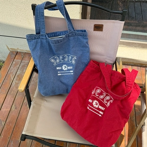 Detailed view of blue and red vintage denim tote bags with paisley patterns on a chair