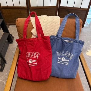Detailed texture of red and blue washed canvas tote bags with retro graphic prints