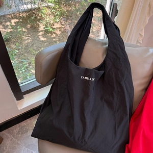 Détail du sac cabas minimaliste en nylon noir avec inscription Camellia imprimée