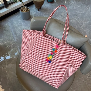 Detail der rot-weiß karierten Segeltuchtasche mit Pompon und Druckknopfverschluss