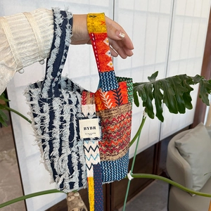 Detail of patchwork denim tote bag featuring white tassels and ethnic patterns