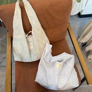 Détails des sacs cabas à carreaux avec écusson magazine sur une chaise vintage