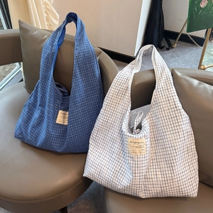 Détail de sacs fourre-tout à carreaux avec écusson magazine sur un canapé gris
