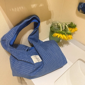 Détail du sac cabas à carreaux bleus avec écusson en texte et décor de tournesols