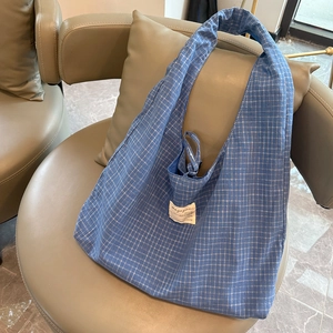 Gros plan du sac cabas à carreaux bleus avec large bandoulière et étiquette tissée