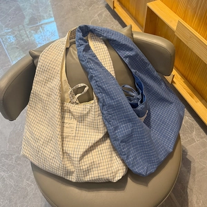 Vue détaillée de grands sacs cabas en toile à carreaux bleu et beige sur une chaise