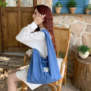 Grand sac cabas à carreaux bleus porté par un mannequin dans un jardin au style rétro
