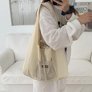 Détail du sac cabas en toile avec une poche à carreaux bleue et une large bandoulière