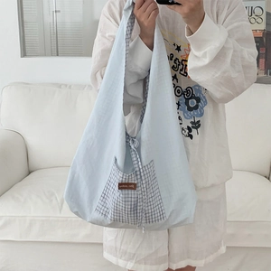 Détail du sac cabas en toile bleu clair avec poche à carreaux et étiquette en cuir